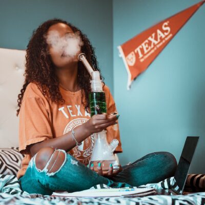 black woman in her bedroom smoking a grav bong