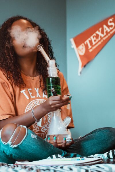 black woman in her bedroom smoking a grav bong
