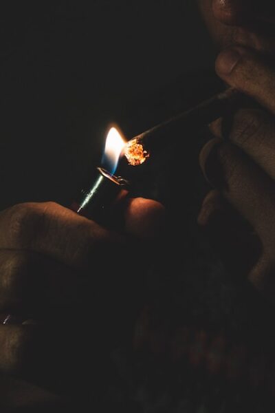person lighting a marijuana joint with a lighter in a dark room